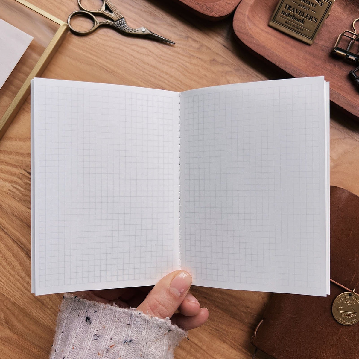 Sarica Studio Floral Notebook, passport TN size, open in hand to show the light gray grid pages