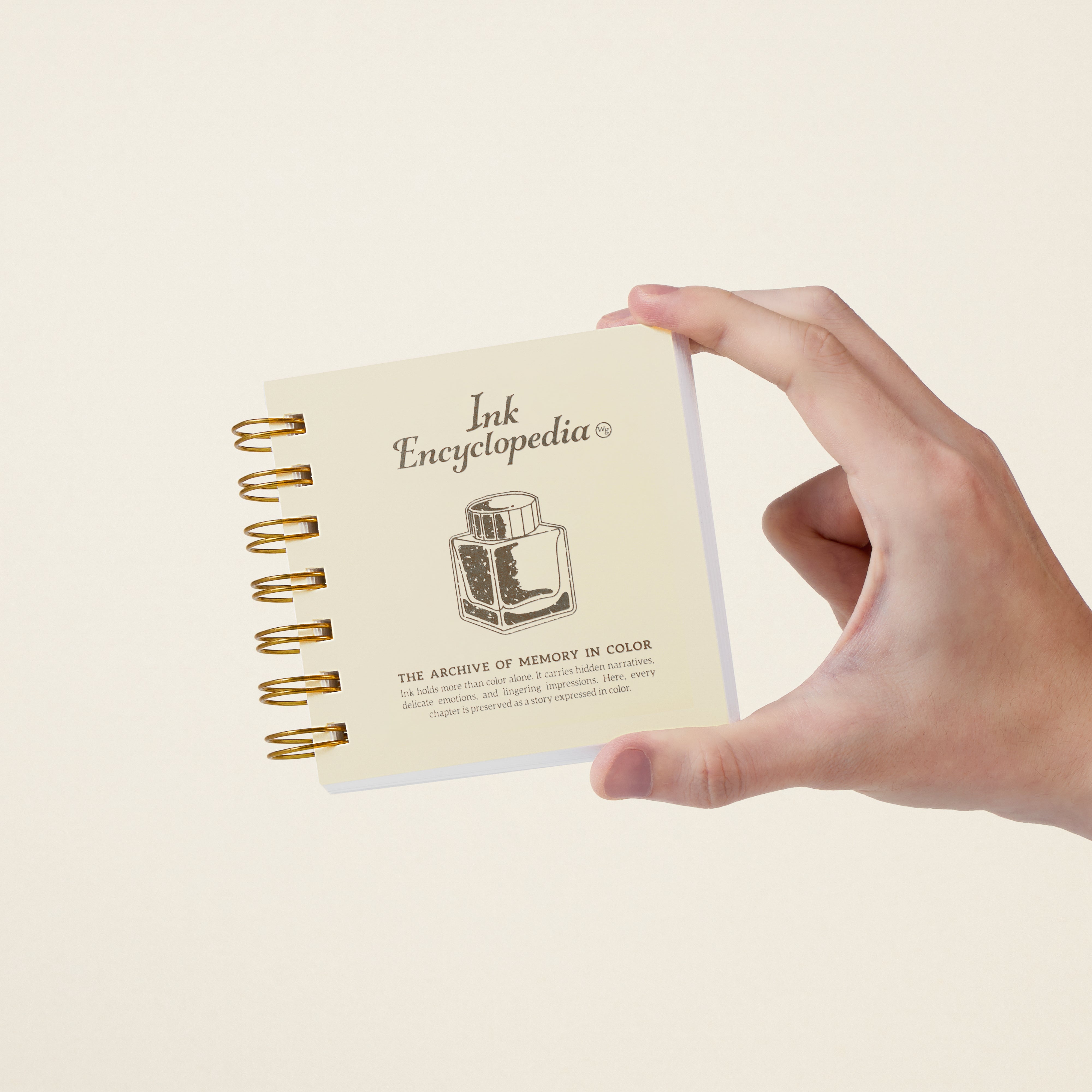 Hand holding small ring bound book titled Ink Encyclopedia