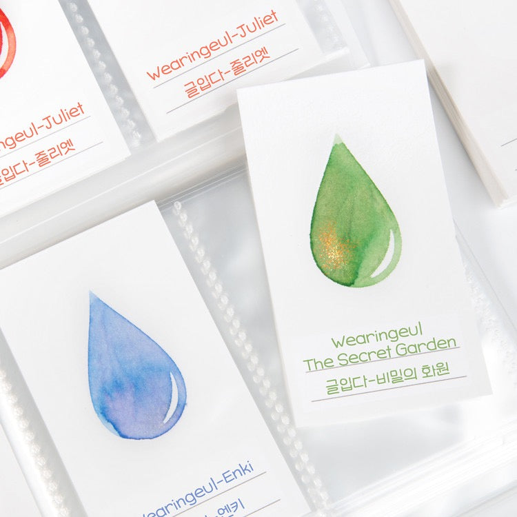 White ink swatch cards with various colors of ink in an ink drop shape