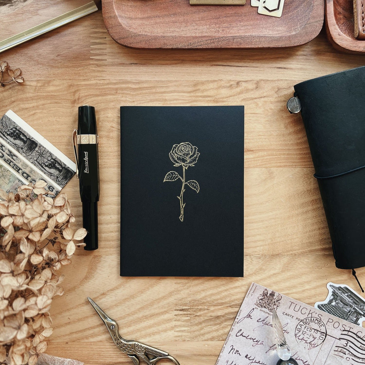 Sarica Studio Rose Notebook, passport TN size, black cover with a gold debossed rose, with a fountain pen and dried hydrangeas