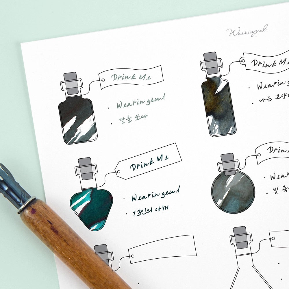 Alice's Potion swatch sheet with gray and teal ink swatches beside a wooden dip pen