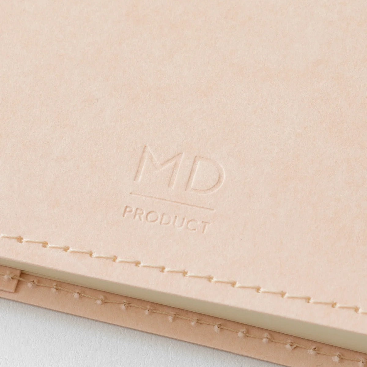 Close-up of the MD PRODUCT logo embossed into the light pink Cordoba paper of the MD Notebook A5 cover