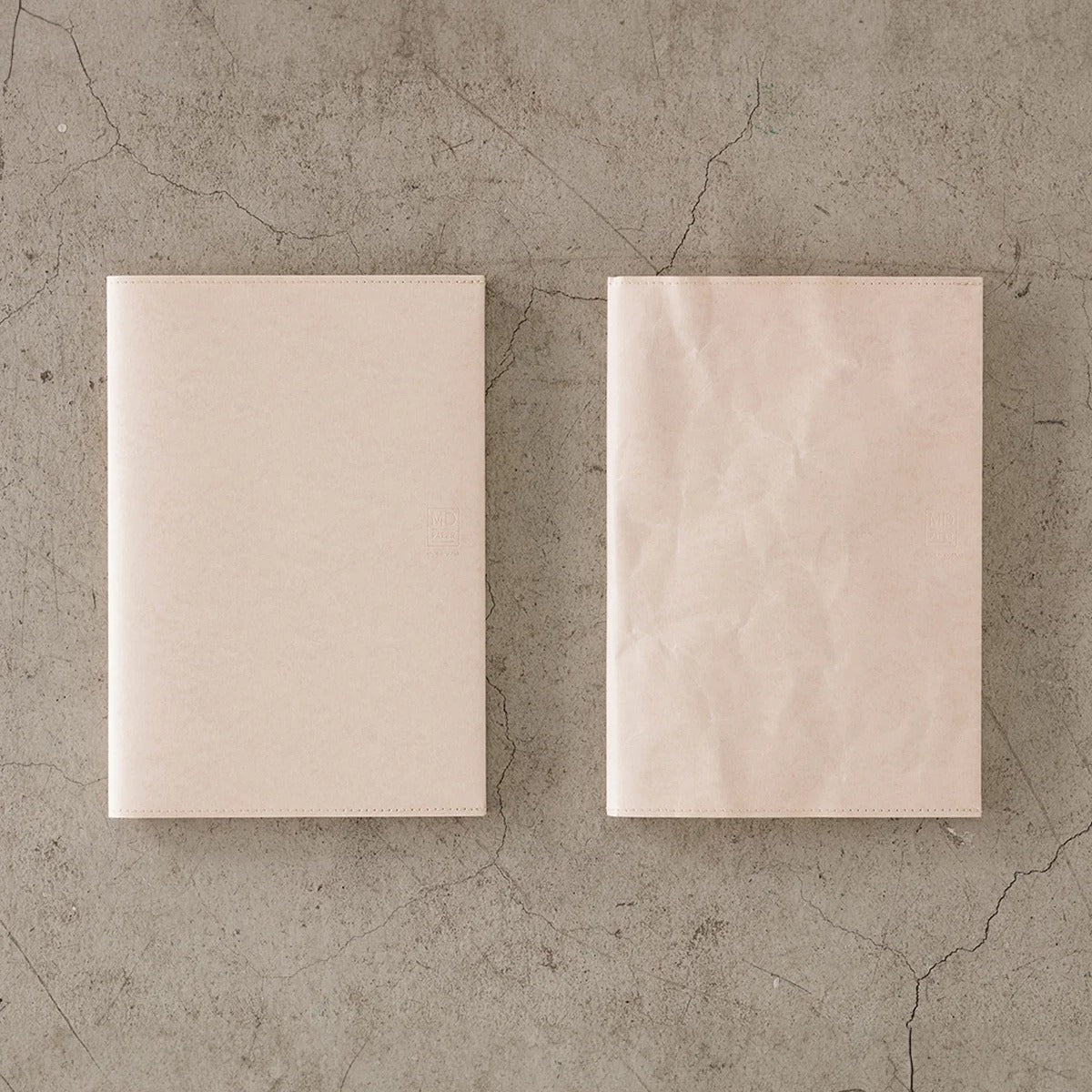 Two MD Notebook A5 paper covers side by side, one new and one creased with age, in light pink Cordoba paper