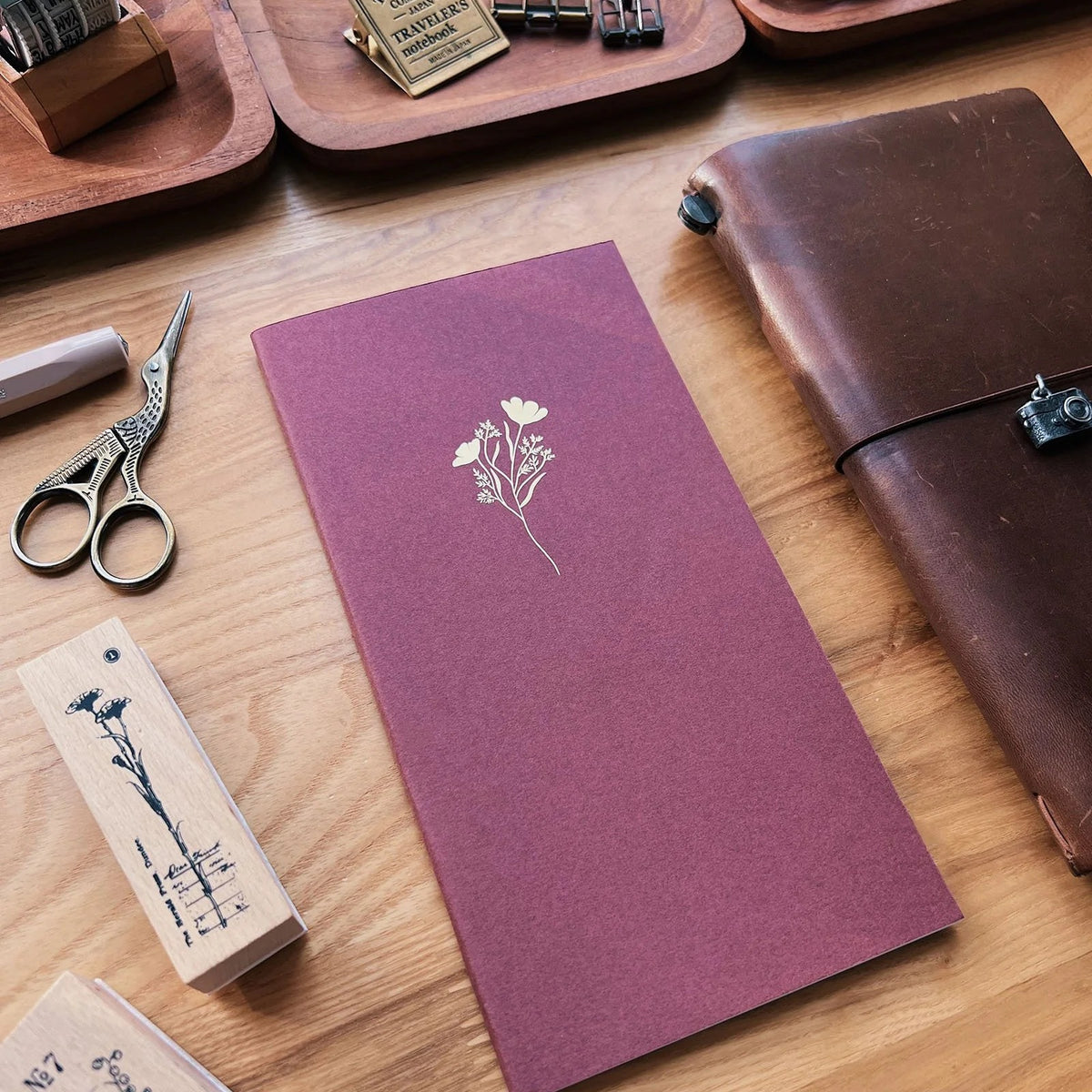 Sarica Studio Floral Notebook, standard TN size, bordeaux cover with a gold debossed floral design, beside a brown leather traveler's notebook