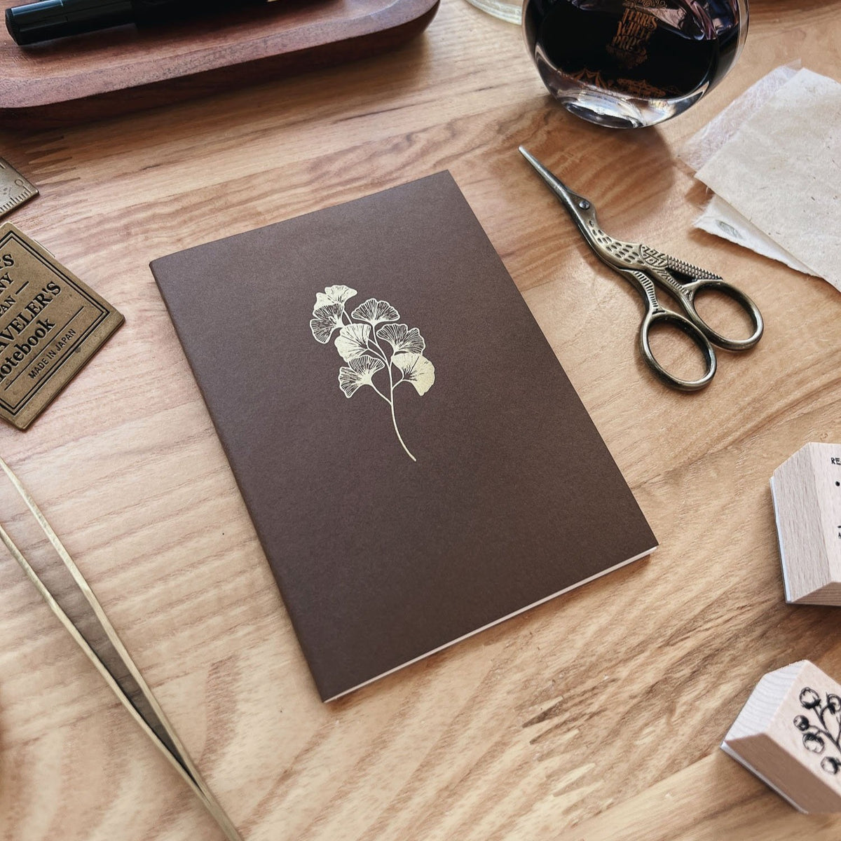 Sarica Studio Ginkgo Notebook, passport TN size, chestnut brown with a gold ginkgo leaf design, shown at an angle