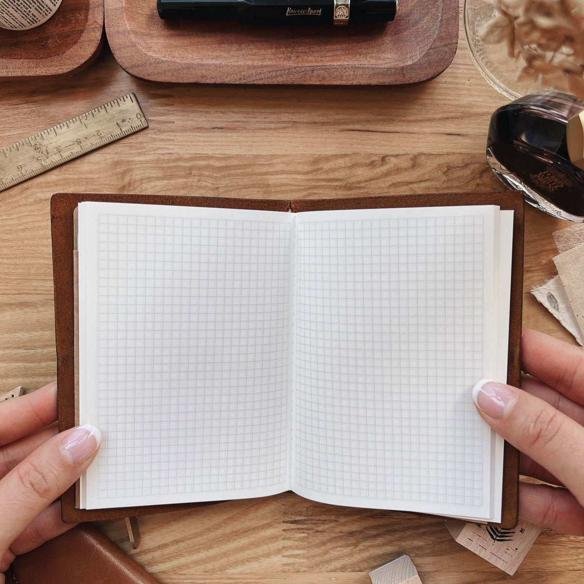 Sarica Studio Ginkgo Notebook, passport TN size, open in a leather passport cover to show the gridded Tomoe River pages