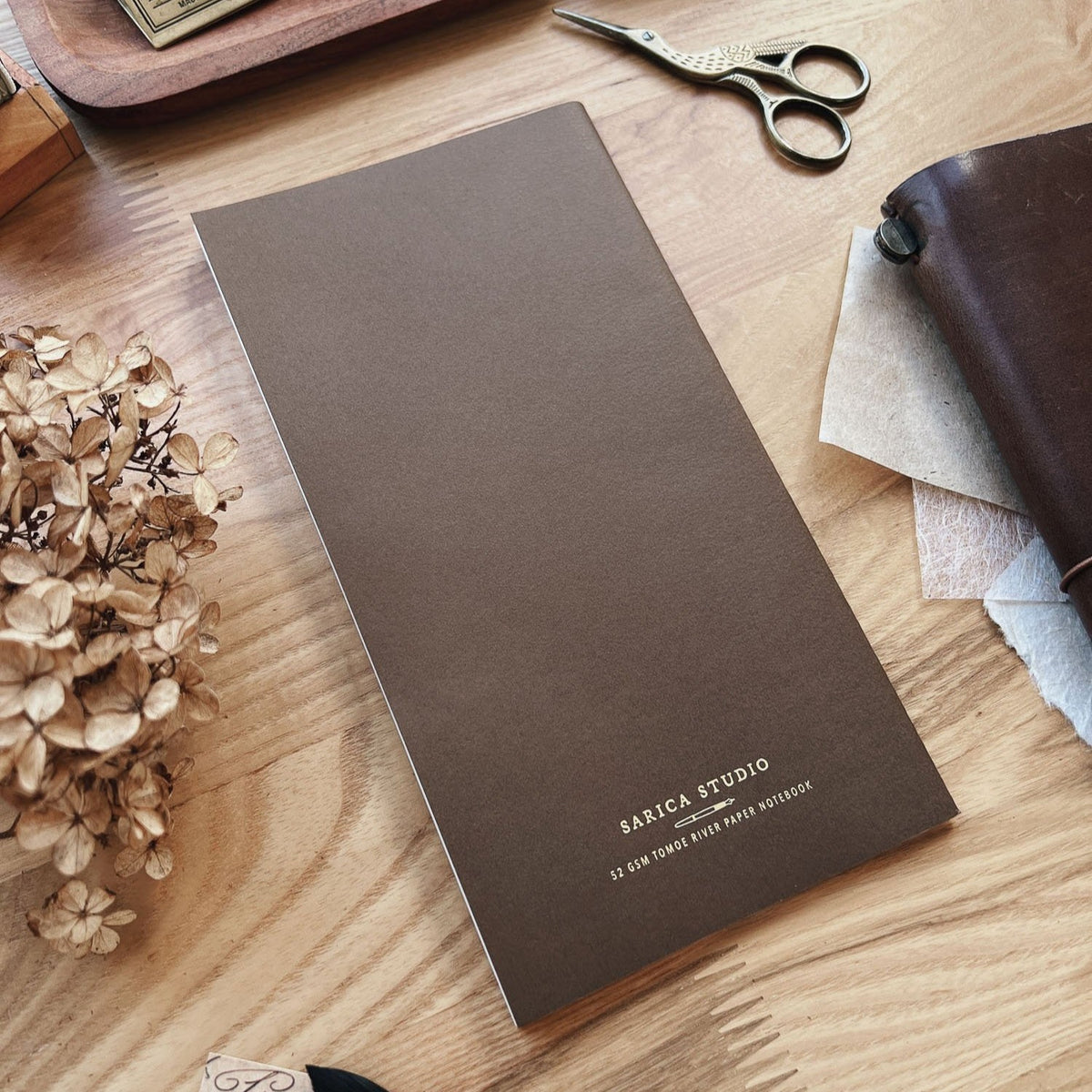 Sarica Studio Ginkgo Notebook, standard TN size, back cover shown at an angle beside dried hydrangeas