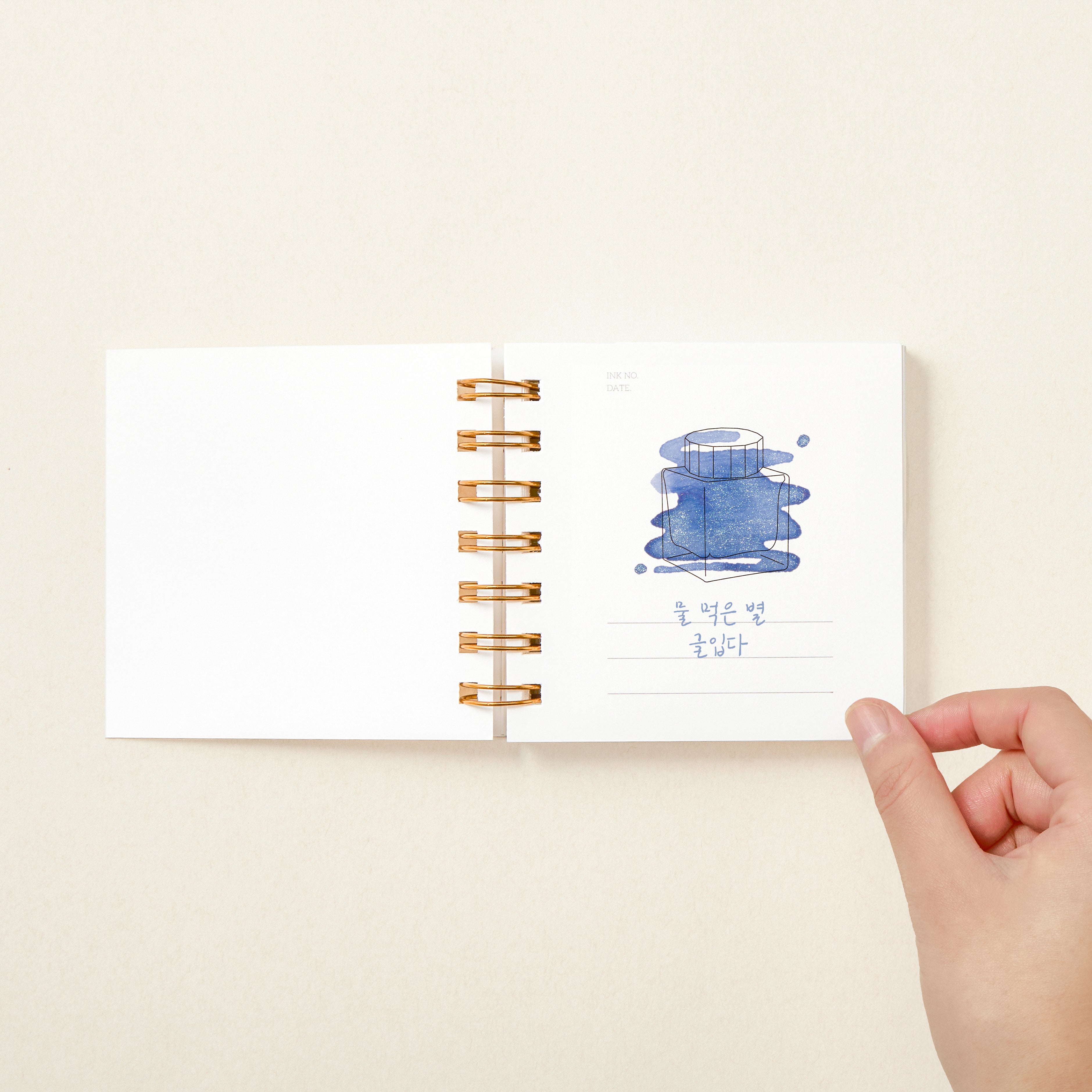 Open ring bound book with drawing of ink bottle filled with ink