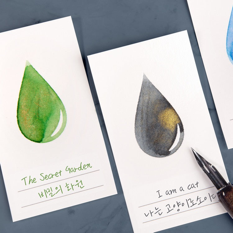 White ink swatch cards with various colors of ink in an ink drop shape