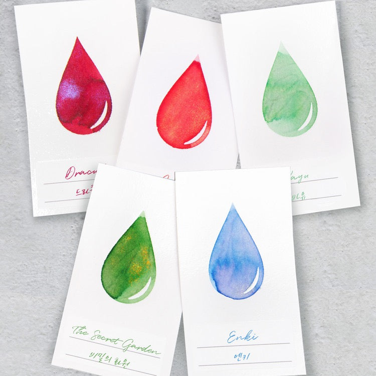 White ink swatch cards with various colors of ink in an ink drop shape