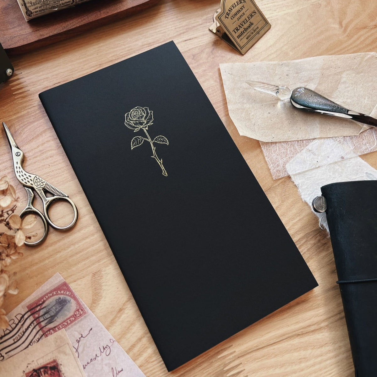 Sarica Studio Rose Notebook, standard TN size, black with a gold rose design, shown at an angle