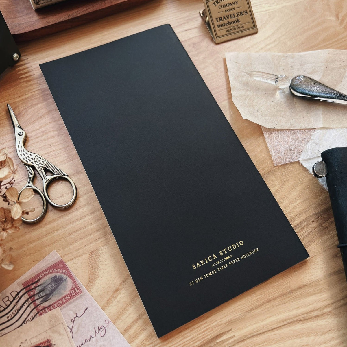 Sarica Studio Rose Notebook, standard TN size, back cover shown at an angle beside a leather traveler's notebook