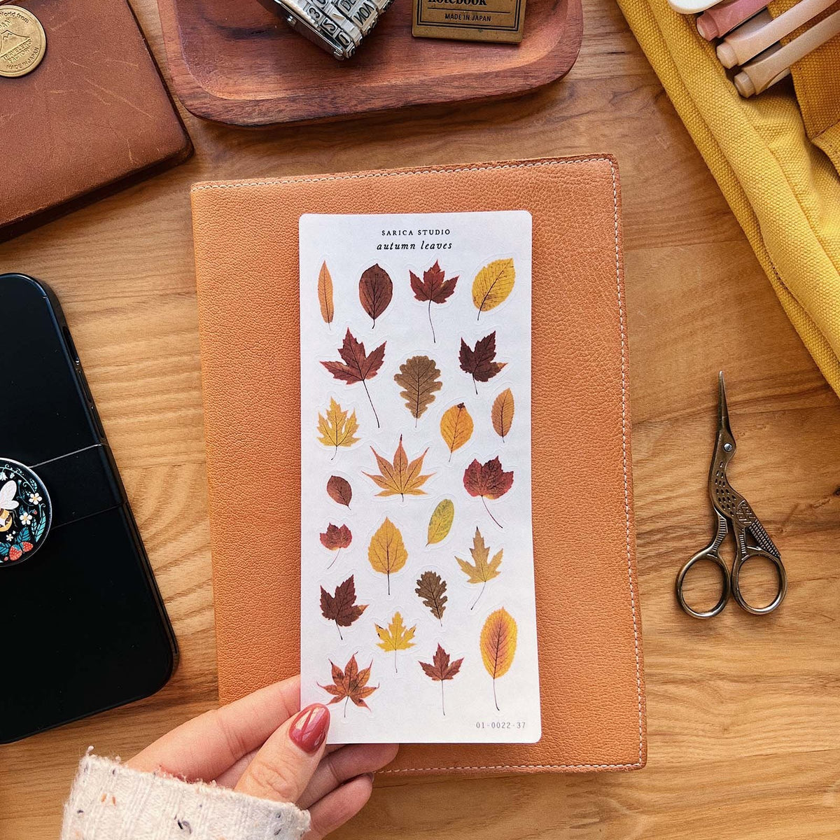 Sarica Studio Autumn Leaves sticker sheet with a traveler's notebook on a desk