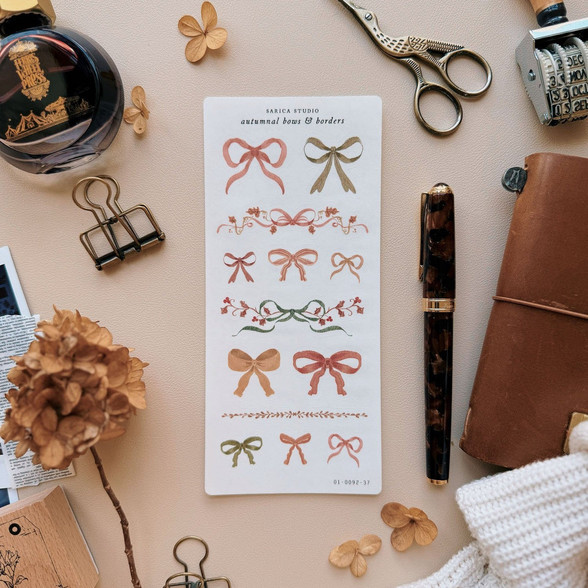 Sarica Studio Autumnal Bows & Borders stickers, sheet on a desk with a fountain pen and dried hydrangeas