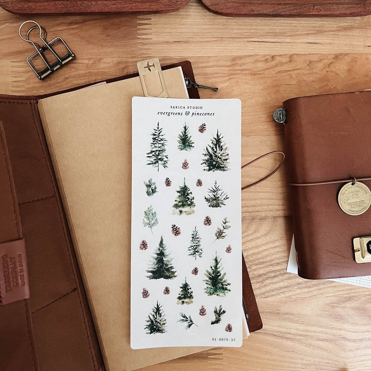 Sarica Studio Evergreens & Pinecones sticker sheet of evergreen trees and pinecones on a kraft traveler's notebook