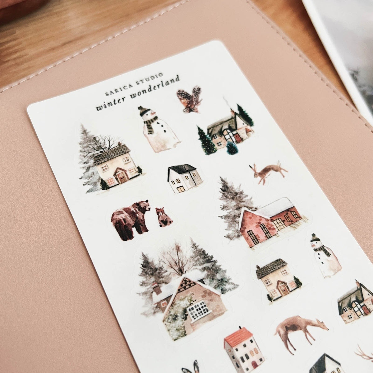 Close-up of Sarica Studio Winter Wonderland stickers with snow-covered houses, a bear, a deer and a fox