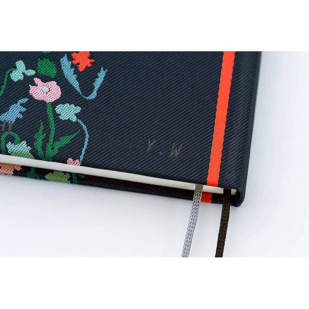Close-up of the Hobonichi Techo 2027 Weeks Petit Bloom cover, showing the texture of the woven navy fabric and the multicolor flowers